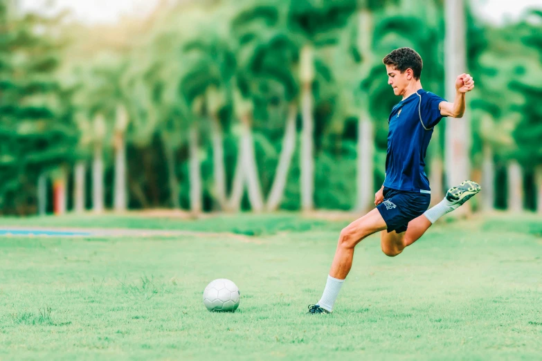 a young man kicking a soccer ball in a field