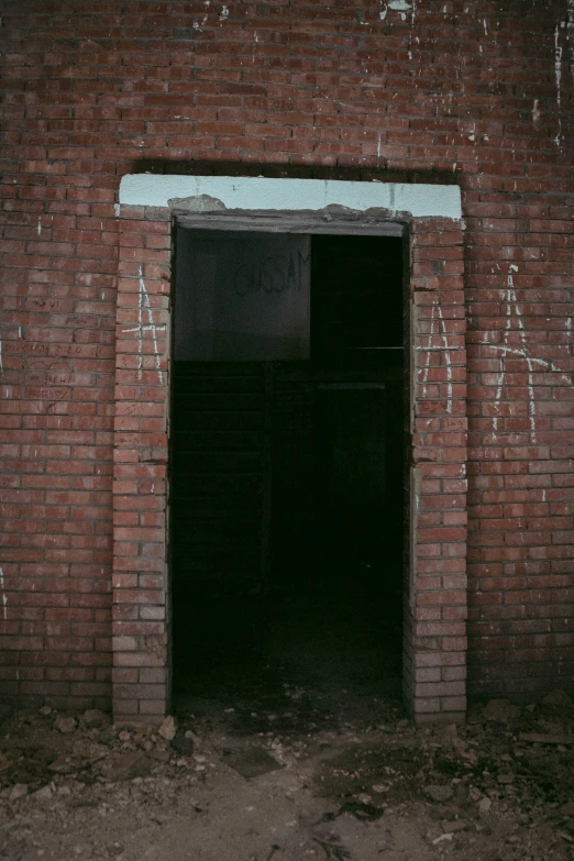 an open doorway in a brick building with graffiti