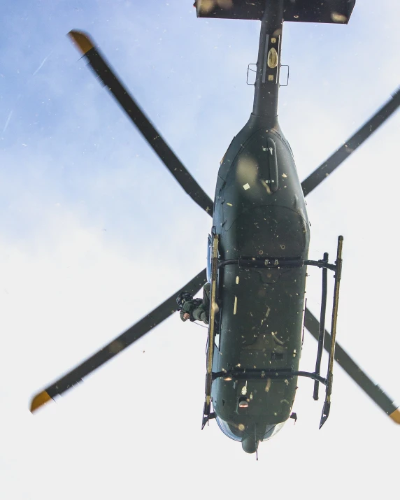 the front end of an army helicopter that is flying through a clear sky