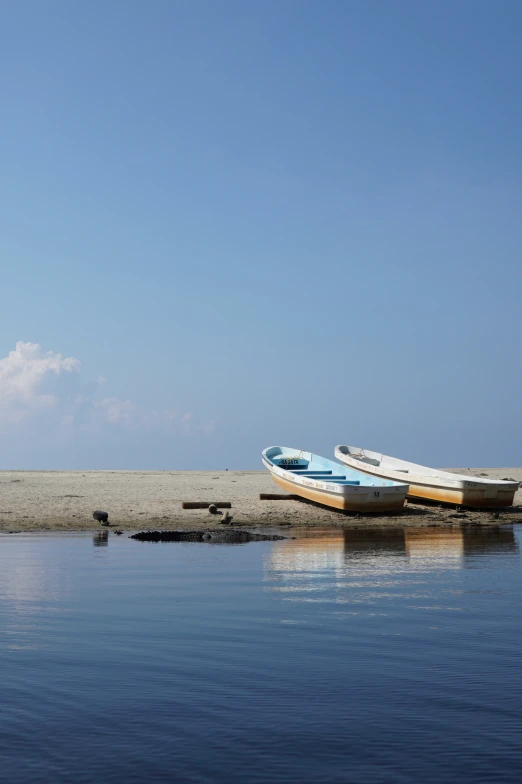 two boats resting on the shore next to water