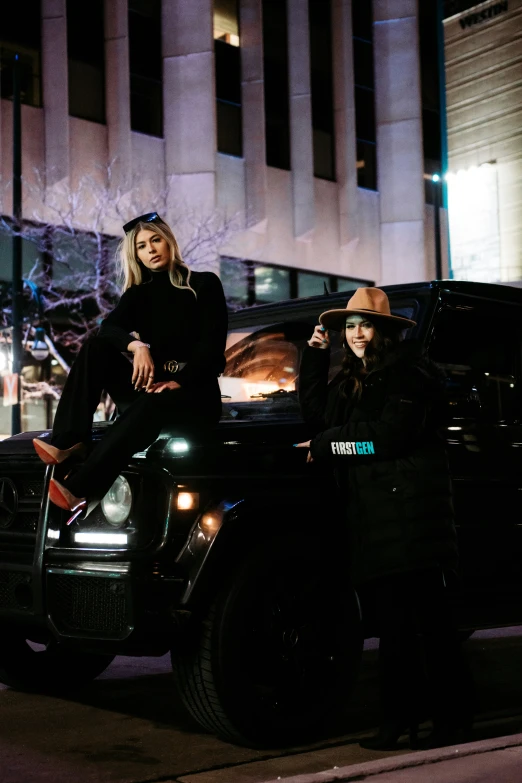 a couple of women in jackets standing next to a truck