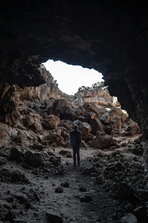 a person in black jacket standing under a cave