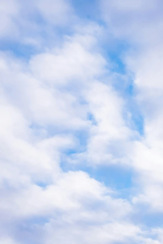 a airplane flying through a cloudy sky in the afternoon