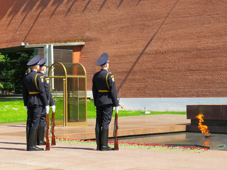 men in uniform standing in front of a memorial