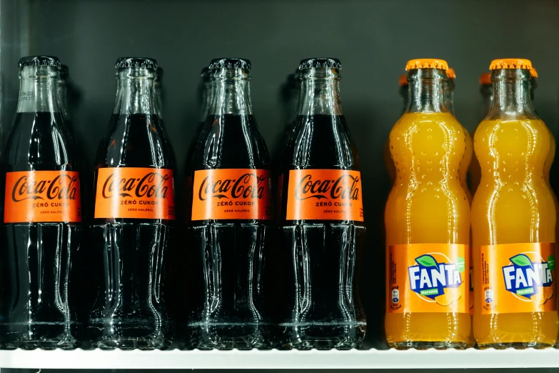 six bottles of orange soda on a shelf