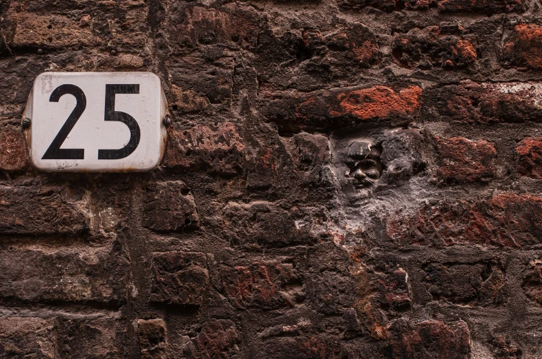 the sign is on a brick wall and reads twenty five