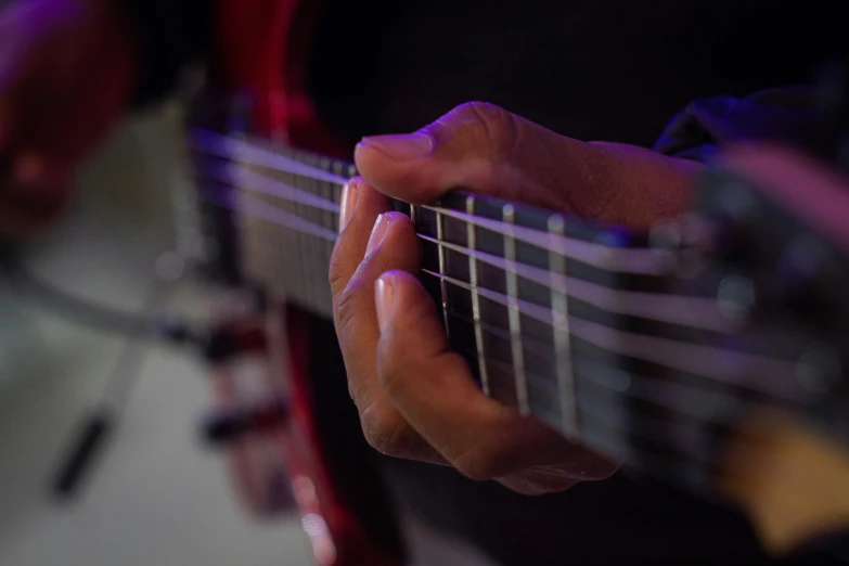 a person with their fingers playing a guitar