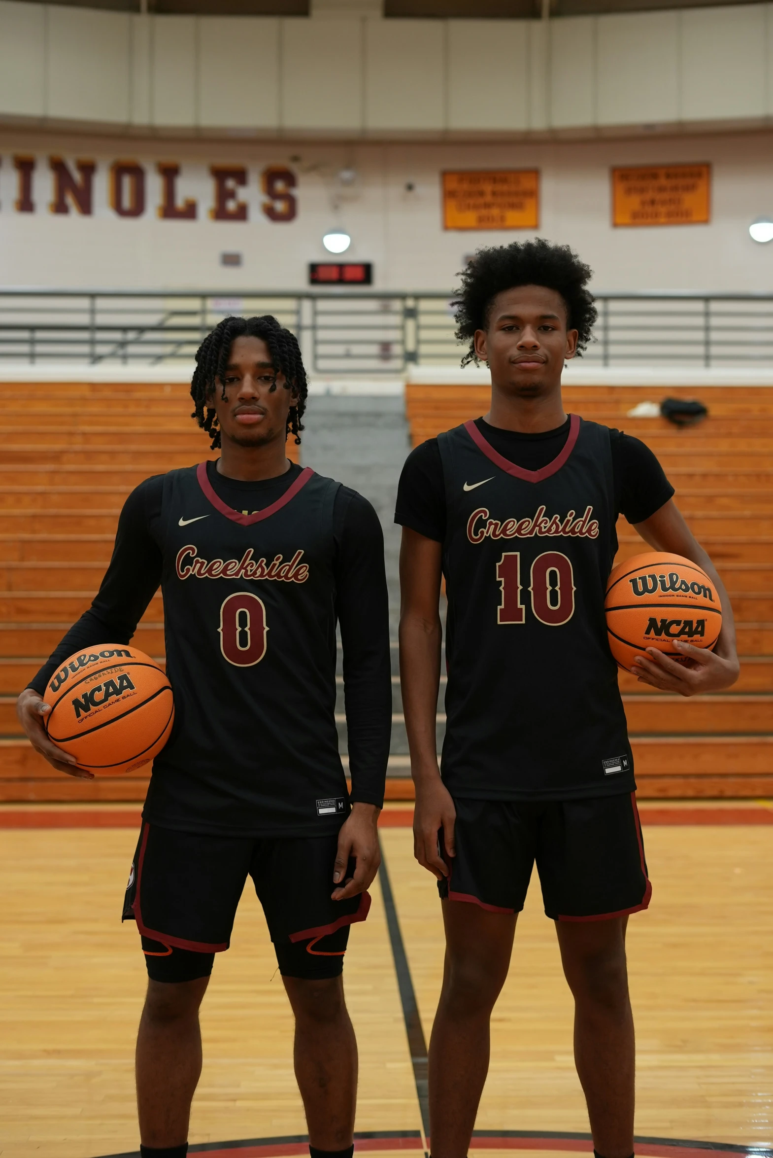 two young men are standing together holding basketballs