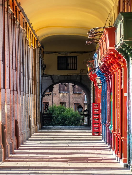 some type of alley with some chairs and a red umbrella