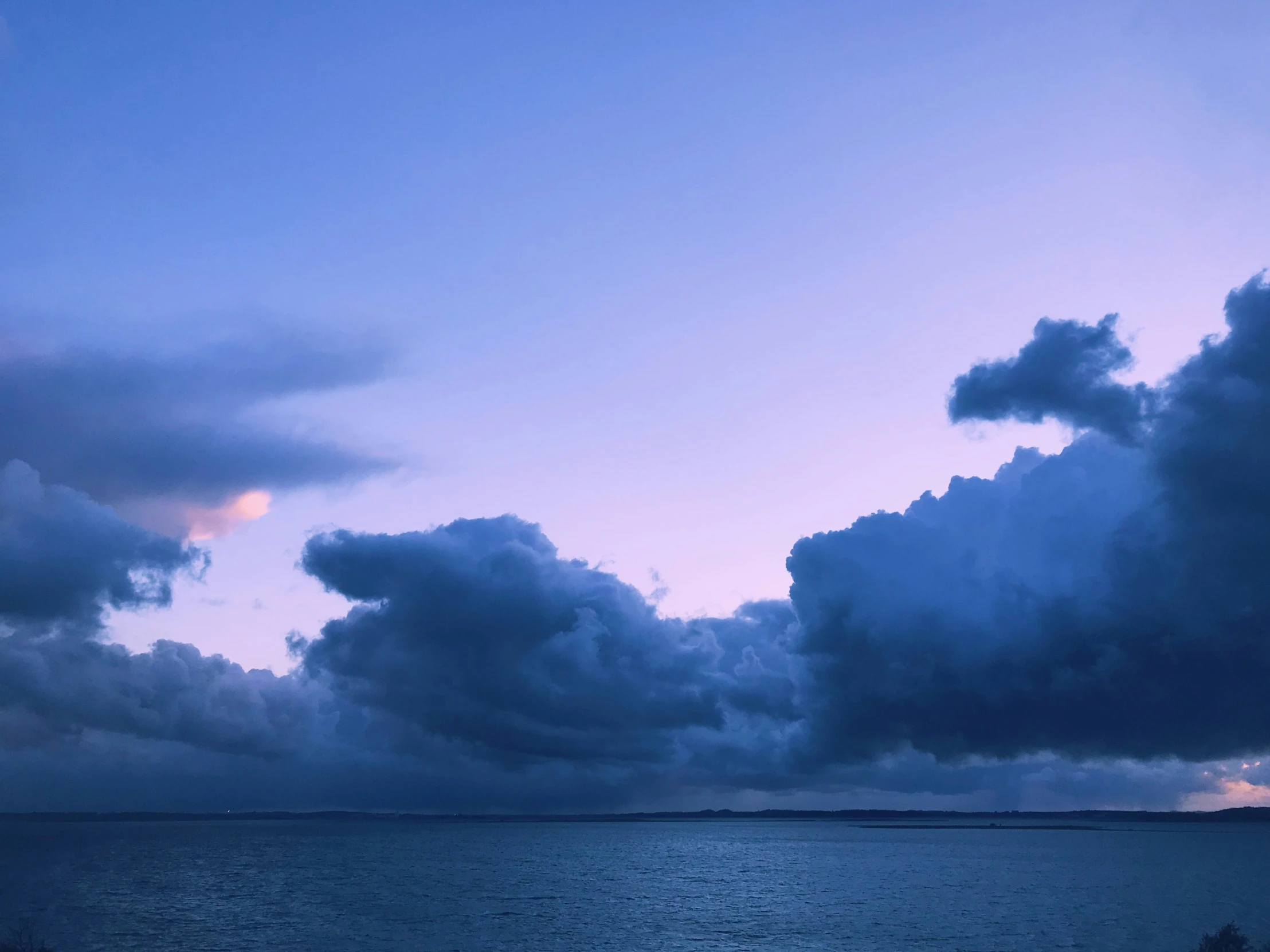 some people with umbrellas standing under a very cloudy sky