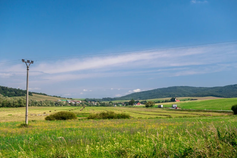 the view of a farm with hills behind it