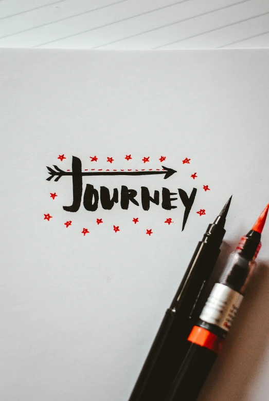 a white piece of paper that says journey on it with writing next to a black pencil