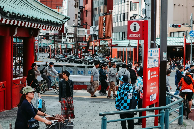 several people walk down a street with a red gate