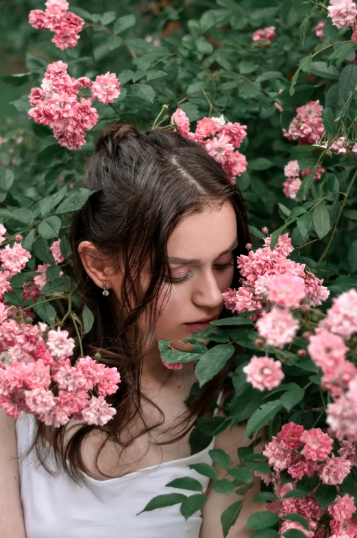 a woman standing behind pink flowers in the forest