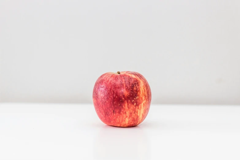 an apple is placed on a white surface