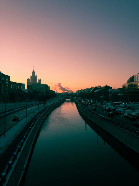 a canal near a city street at sunset