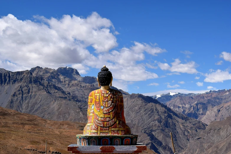 buddha statue surrounded by mountains under a blue sky