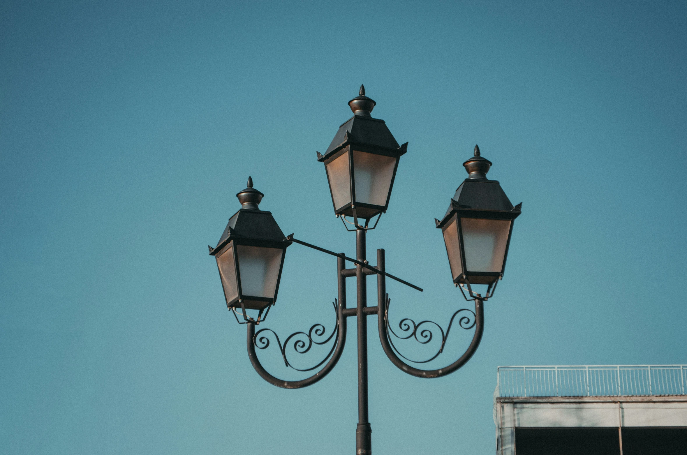 three old fashioned street lights on a tall lamp post