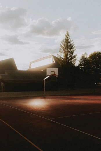 the basketball hoop is empty as the sun goes down