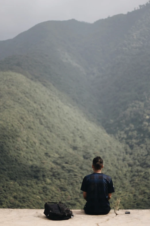 a man sitting on a rock overlooking a valley