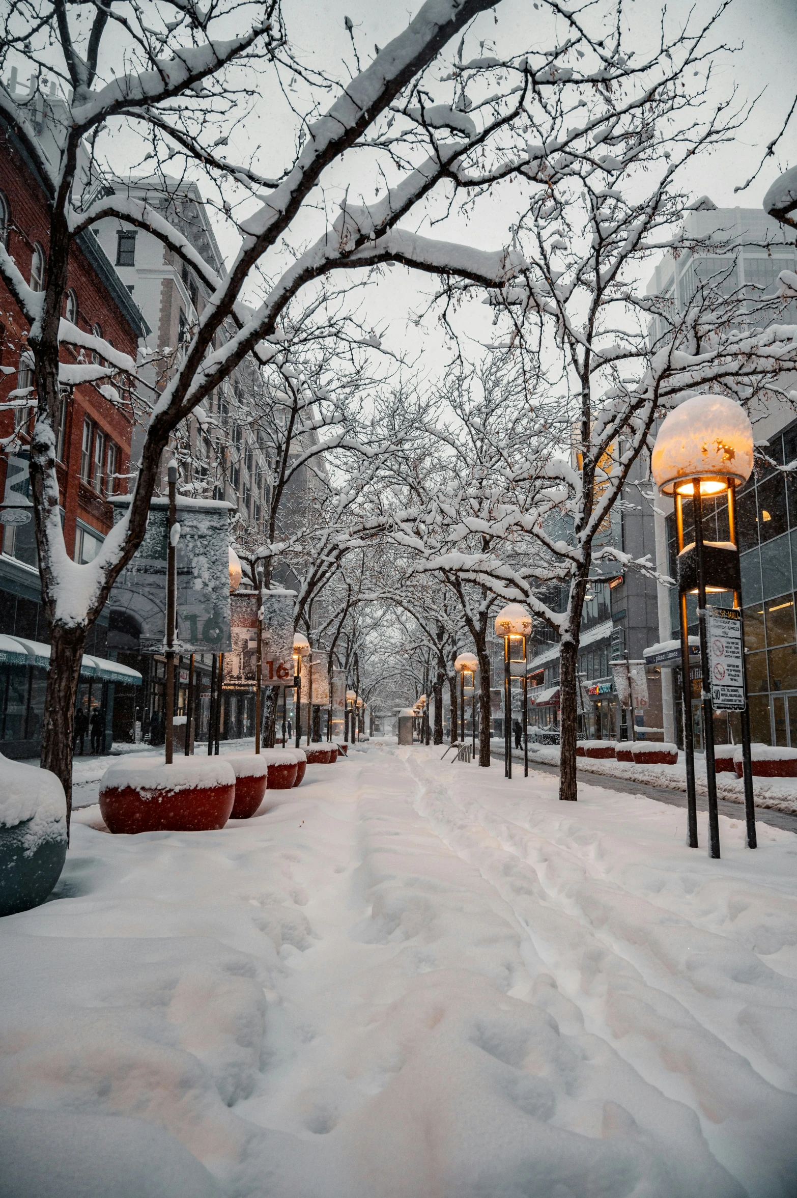 an empty sidewalk next to buildings covered in snow