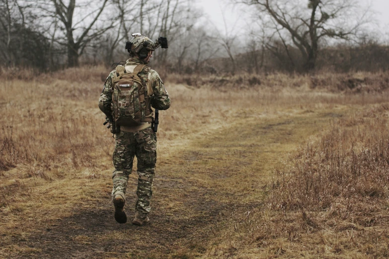 a man in camouflage walking through a field