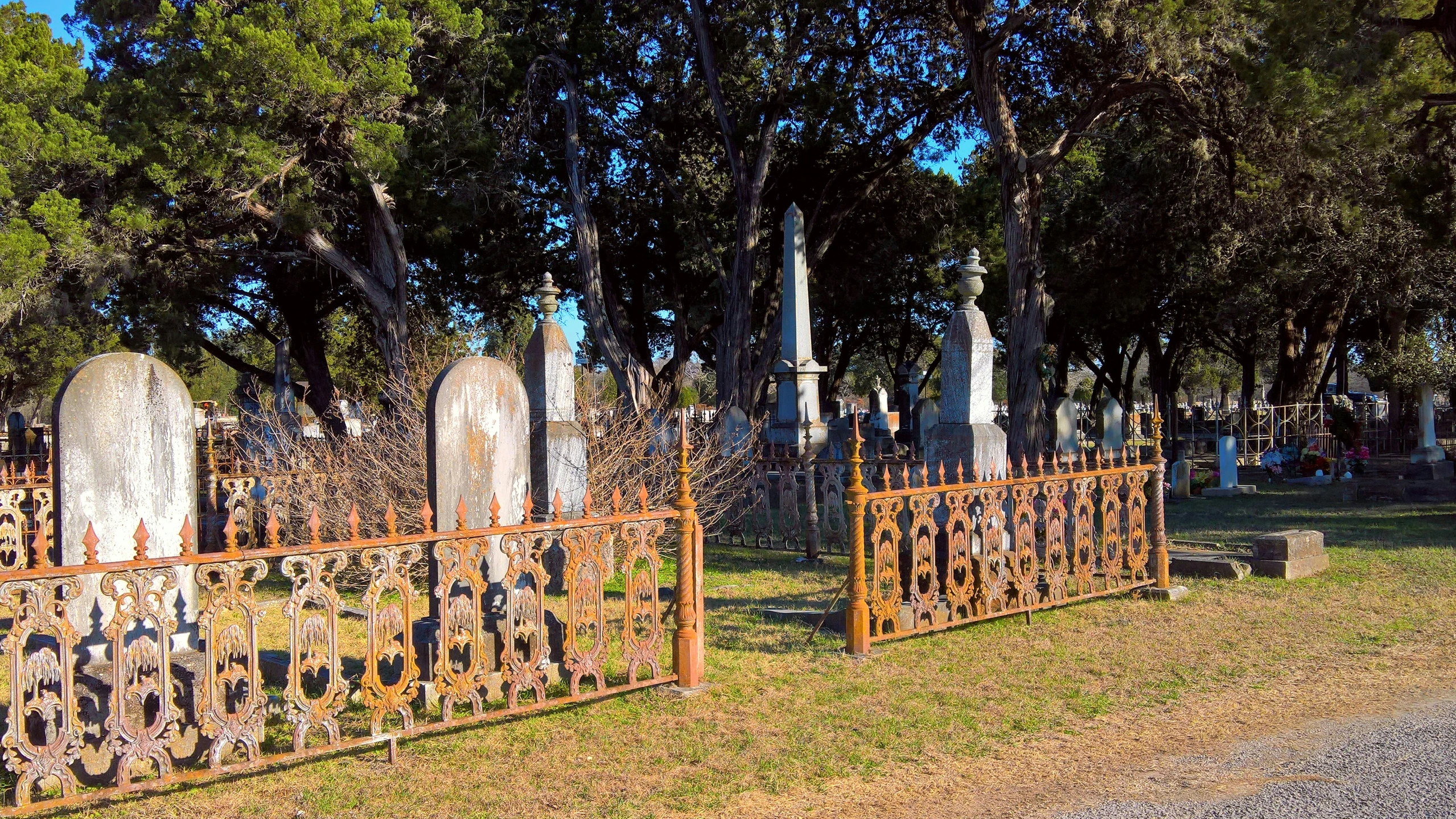a row of tombstones next to trees and dirt