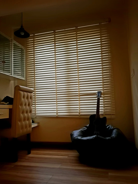 a guitar sitting on a bean bag chair in front of a window