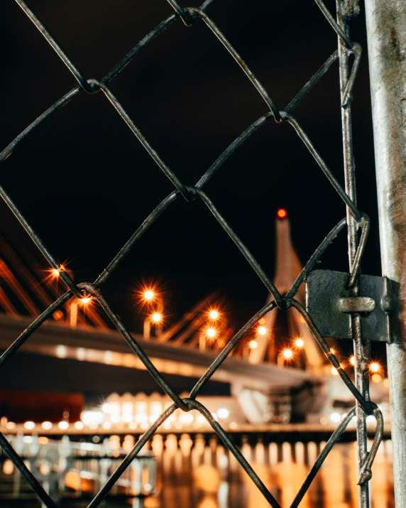 a large train and building lights through a fence