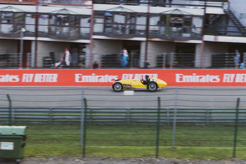 a yellow race car driving past a tall building