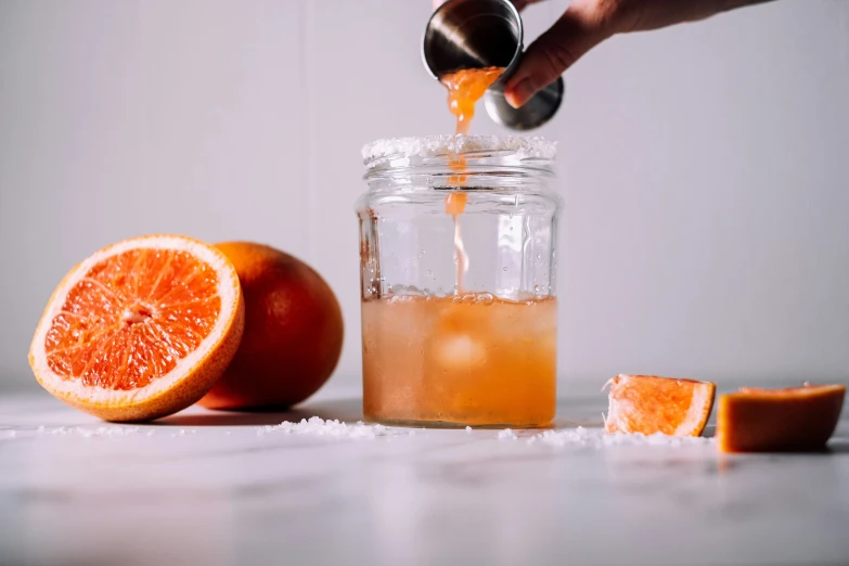 a jar full of orange juice with pieces of orange