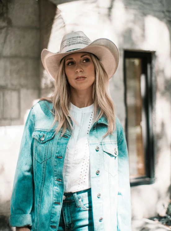 a woman wearing a cowboy hat and denim jacket
