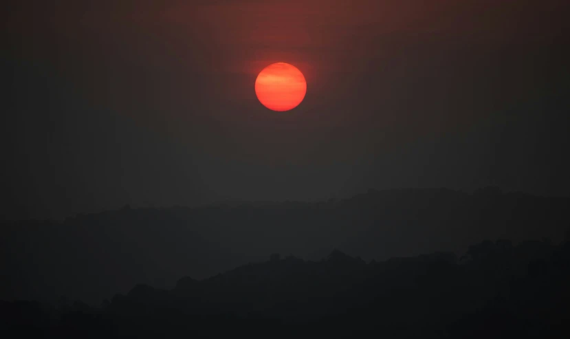 the sun is setting over a mountain range