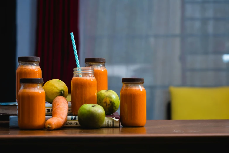 various bottles of food are stacked with carrots and apples