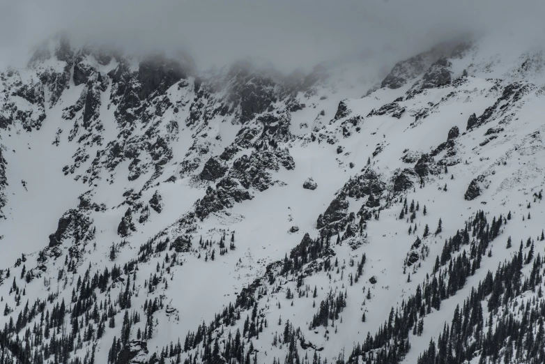 a mountain covered in snow and low clouds