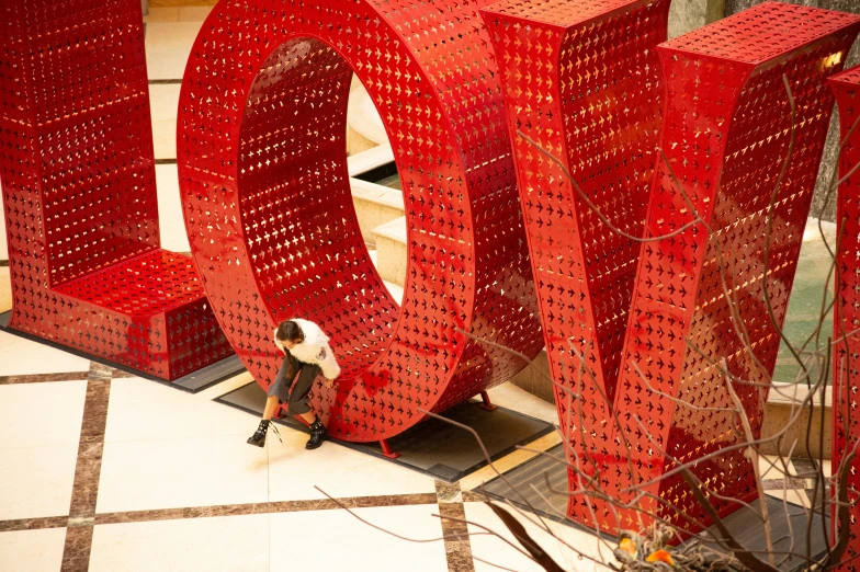 a person standing next to large red sculpture