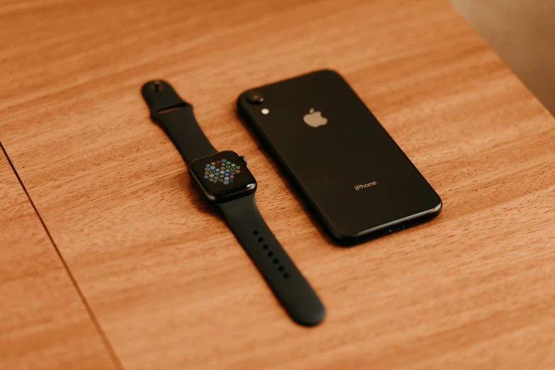 an iphone and watch on the wooden surface