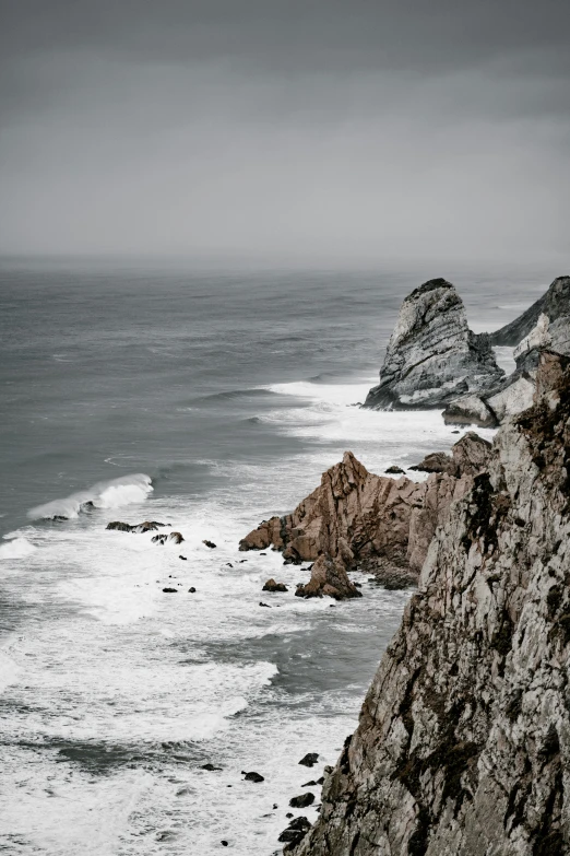 a man standing on the side of a cliff next to the ocean