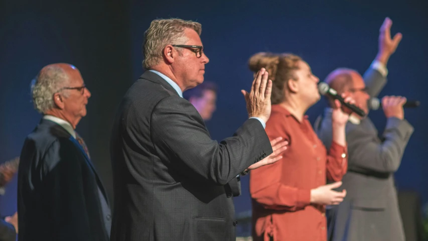 people applauding while standing with their hands raised