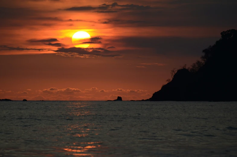 a boat sails through the ocean at sunset