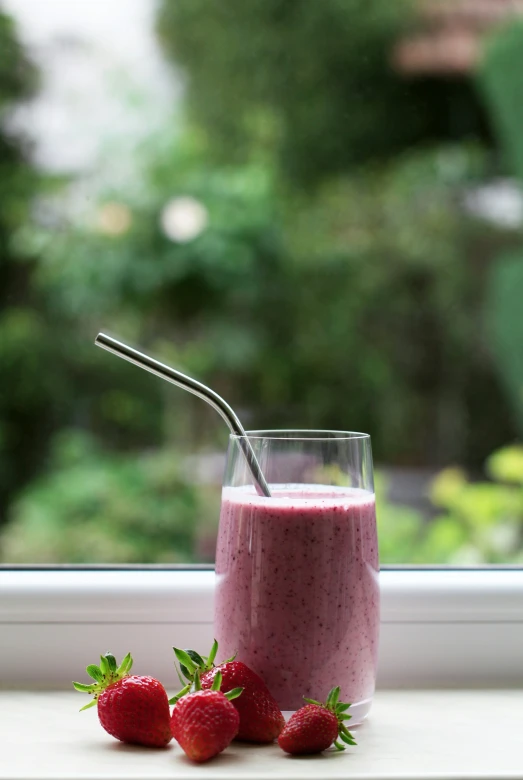 a strawberry and berry shake sitting on top of a window sill