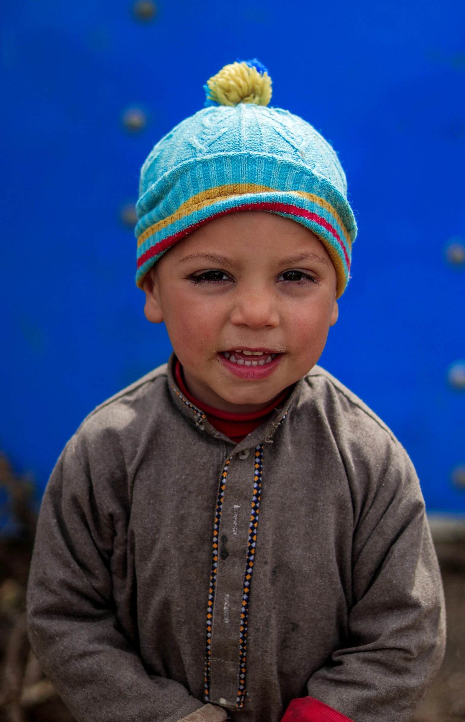 a little boy wearing a hat and smiling for the camera
