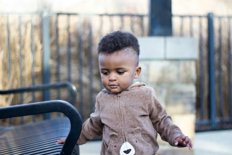 young black boy walking by a park bench in the park