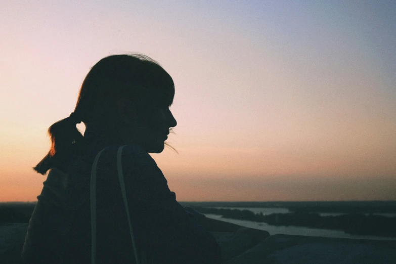 the silhouette of a girl looking into the distance