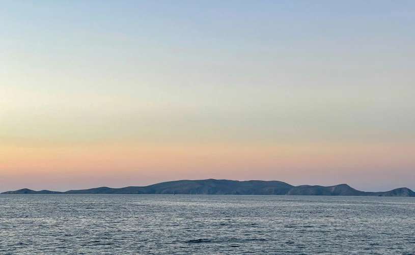 a person in a boat on the ocean near a hill