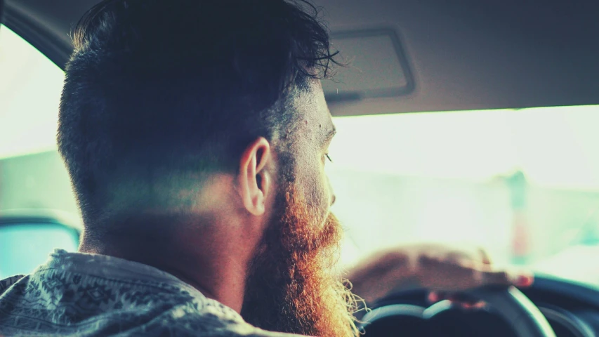 a man with long hair and glasses on top of a steering wheel