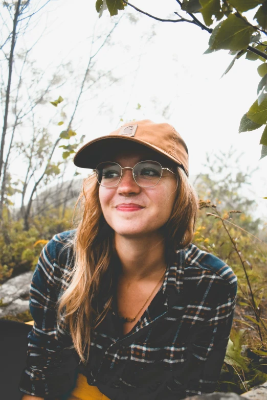 girl with brown hat and sunglasses sitting on rocks