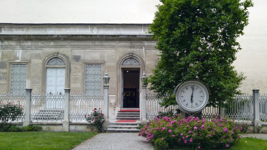 a po of a house with a clock and some plants