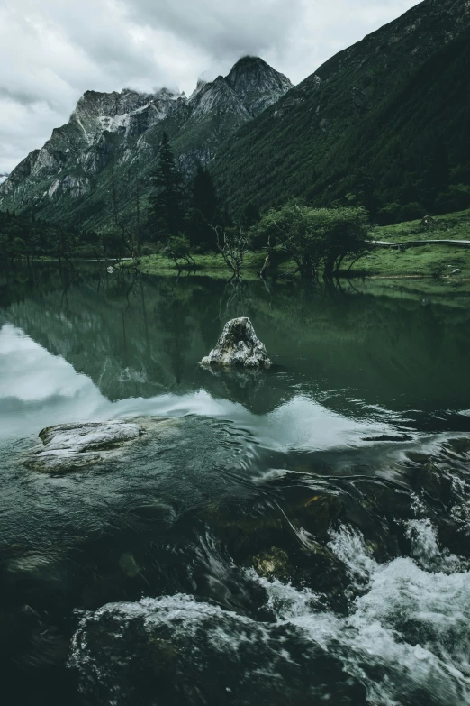 a mountain lake is in the midst of an overcast day