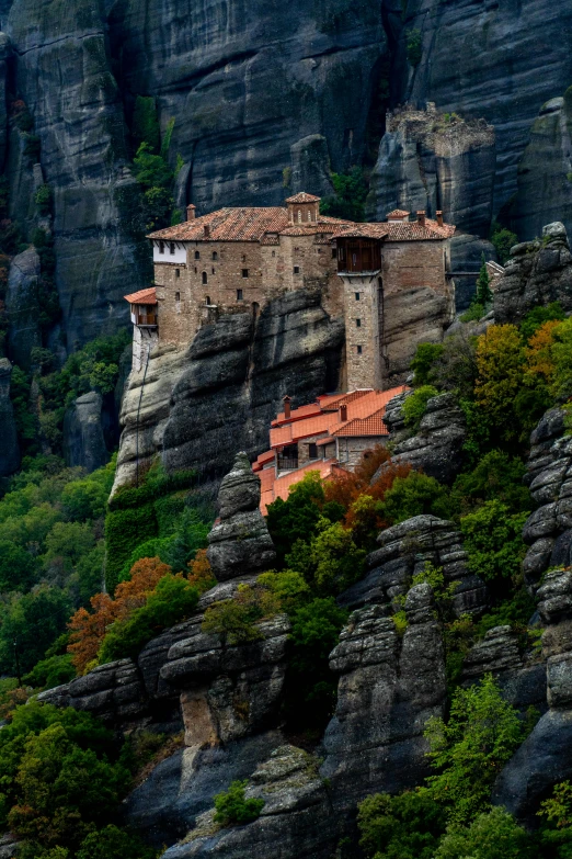 a small castle on top of a mountain near many trees